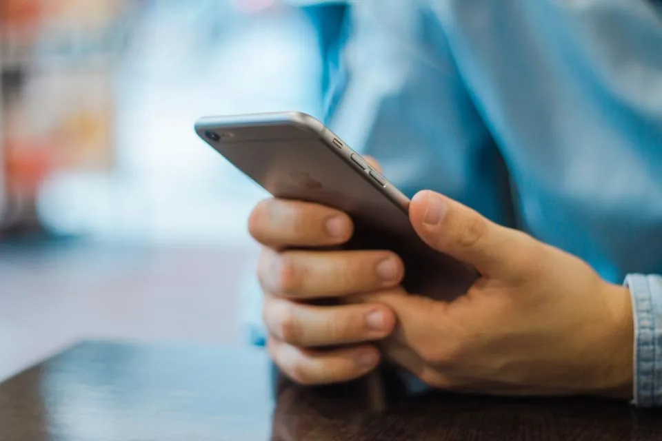 A hand holding a phone above a table, typing a message