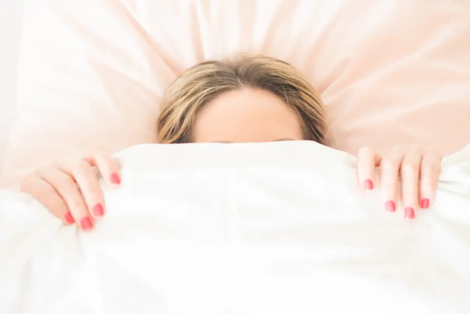 Une femme se cache sous sa couette, seuls ses yeux dépassent